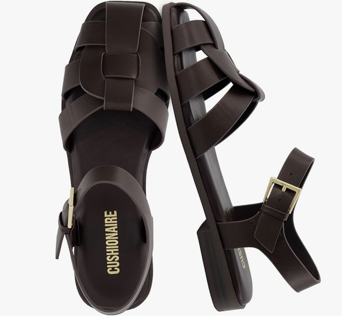 A pair of black Cushionaire Lane fisherman sandals featuring a wide criss-cross strap design and a chunky lug sole on a transparent background.