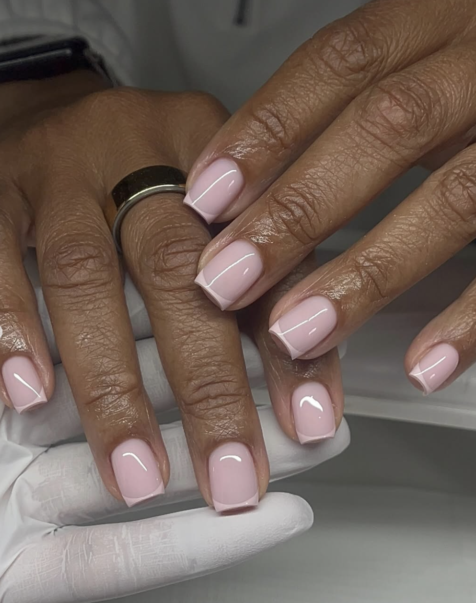 A French manicure on short, clean-cut square nails featuring a sheer blush pink base and crisp white micro tips.