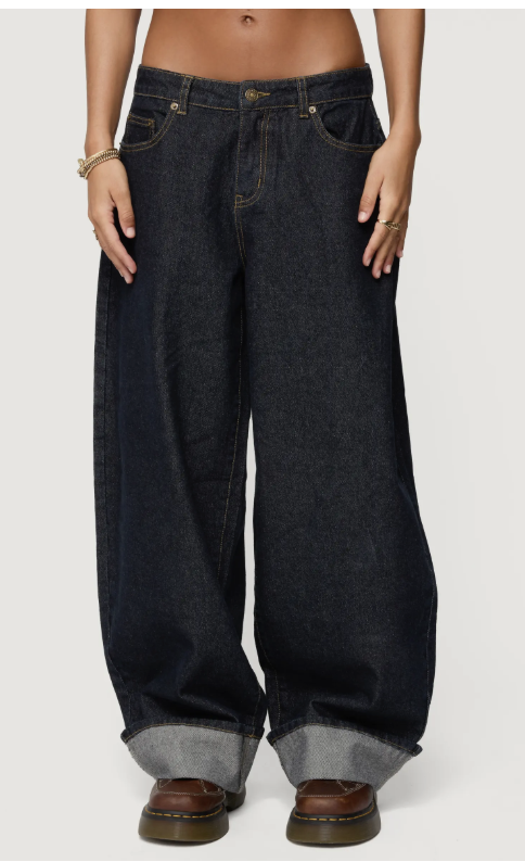 Product shot of Edikted Kella oversized low-rise dark-wash jeans with a wide-leg fit and large cuffed hems, featured as a key item for a relaxed graphic tee outfit.