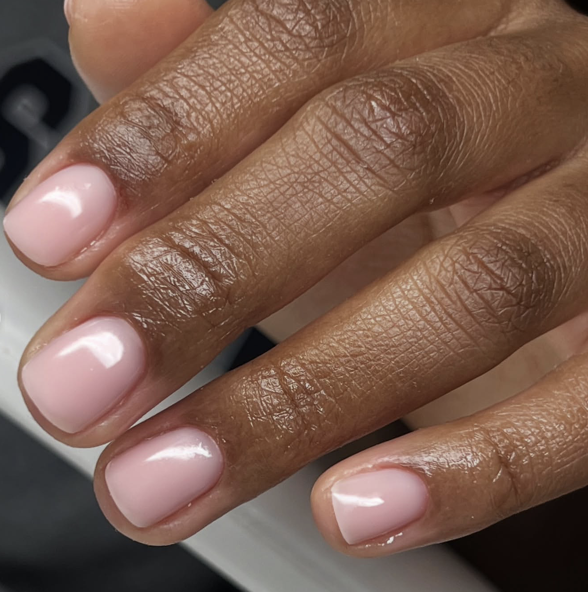 Short square nails with a sheer rose-tinted polish and a high-shine, "bathwater" finish.