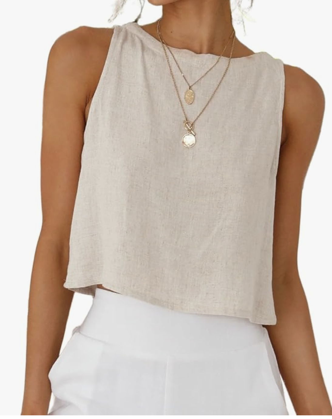 A woman wearing a beige sleeveless linen crop top and white high-waisted pants, styled for a breezy summer BBQ look.