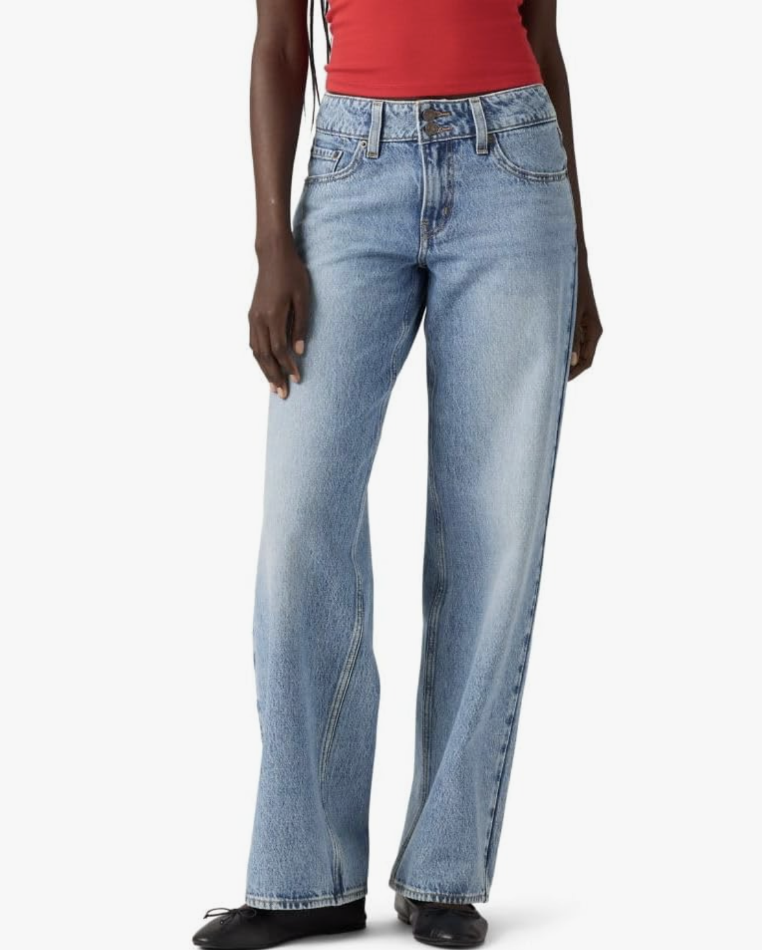 A woman wearing Levi's Superlow Loose straight-leg jeans in a light blue wash, styled with black ballet flats.