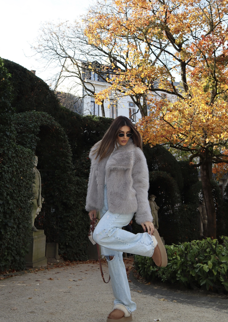 Gray fluffy jacket and pale ripped jeans with tan platform shoes.