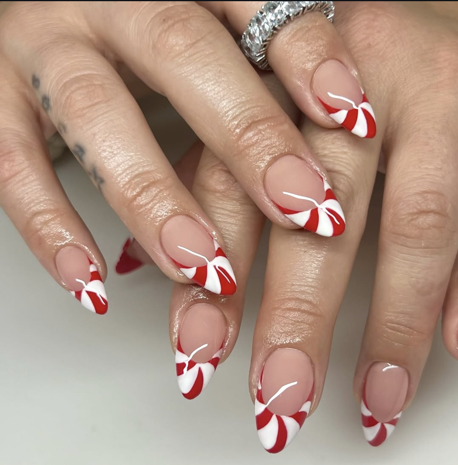 Sheer pink nails with red and white candy cane French tips