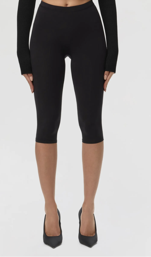 Woman wearing black high-waisted capri leggings that hit just below the knee, featuring a sleek compression fit.