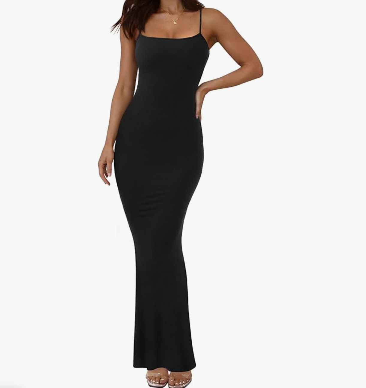 A full-length view of a woman wearing a fitted black slip maxi dress with thin spaghetti straps and a low back, showing a sleek bodycon silhouette.
