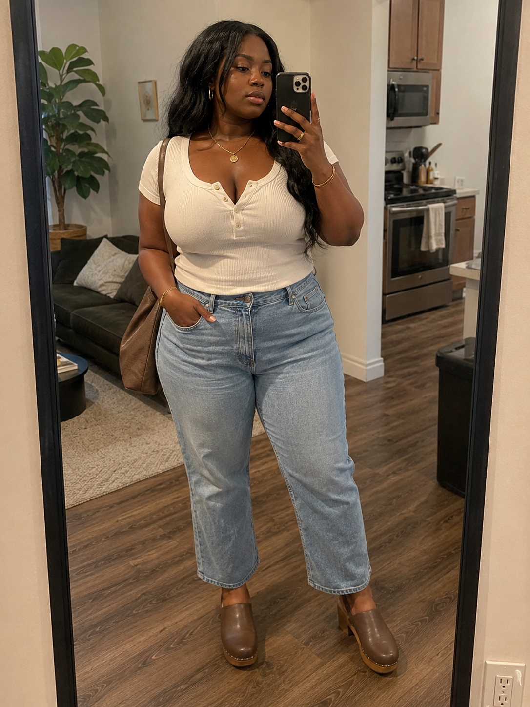 Woman wearing a white ribbed henley top, light blue cigarette jeans, and brown leather clogs.