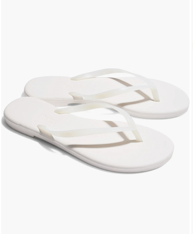 A close-up view of minimalist clear matte rubber thong sandals with a flat white sole against a white background.