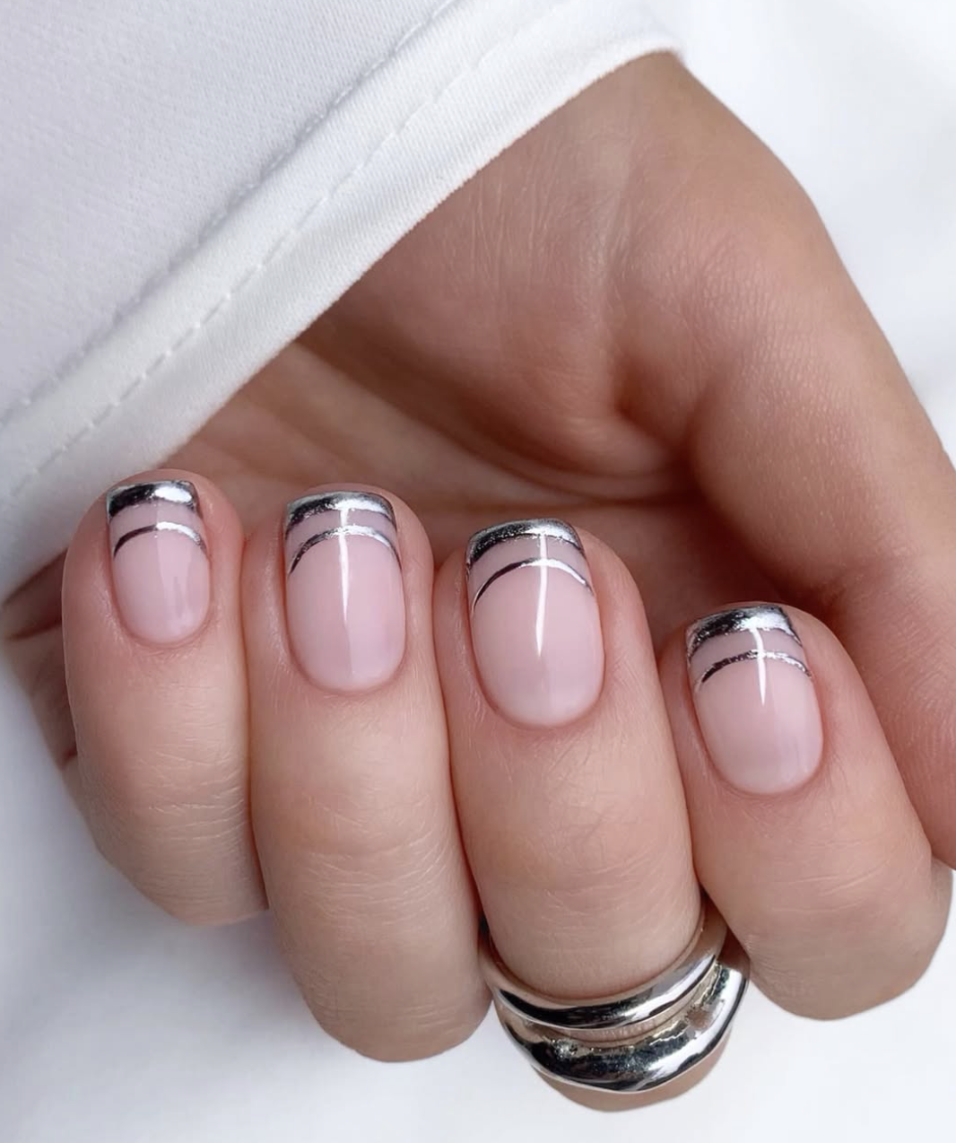 Short square-oval nails with a sheer pink base featuring two stacked, ultra-thin metallic silver French tip lines.