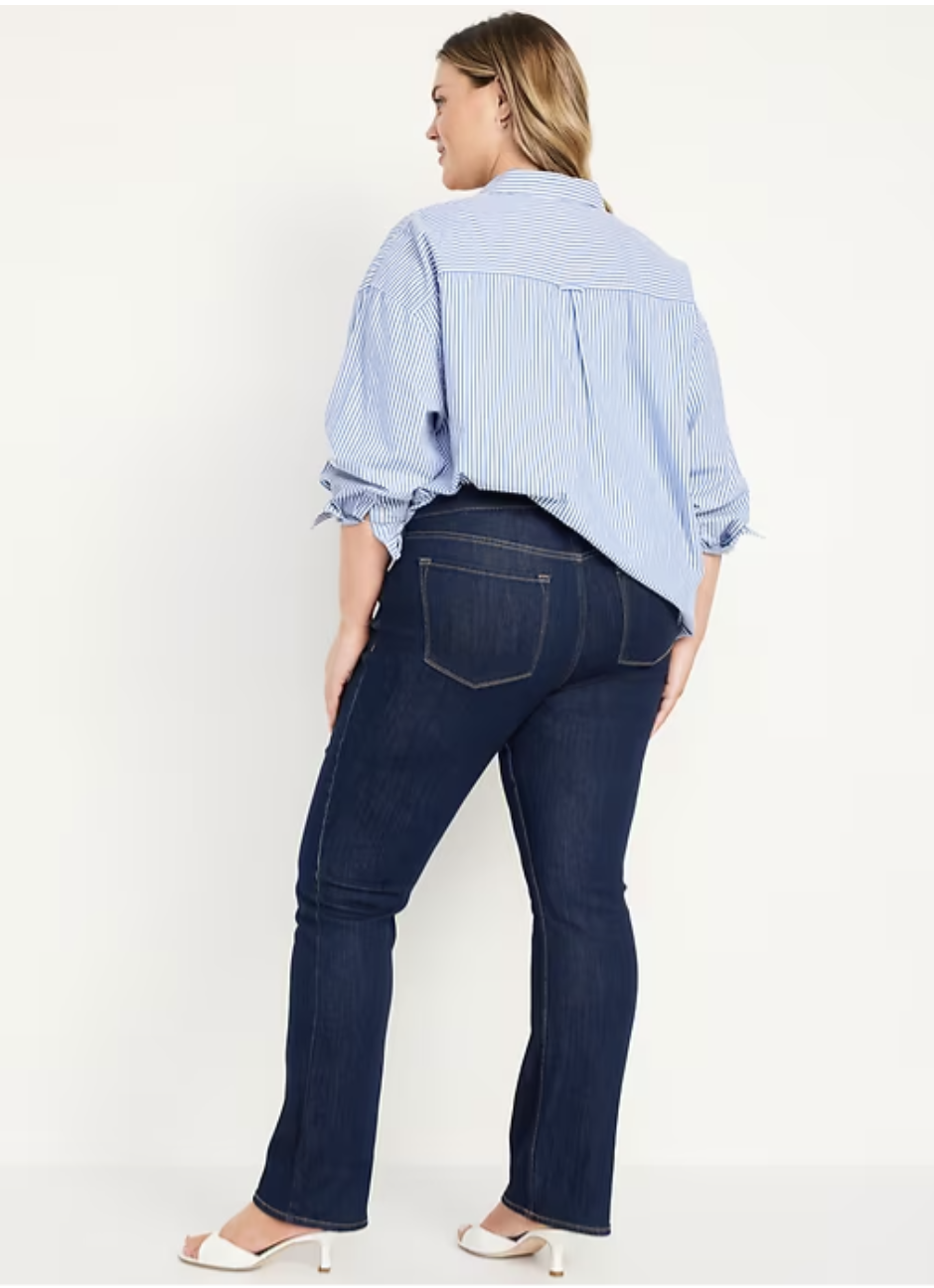 A woman wearing dark wash Old Navy Mid-Rise Wow Boot-Cut Jeans in a petite fit, styled with heels to show off the flattering leg-lengthening silhouette.