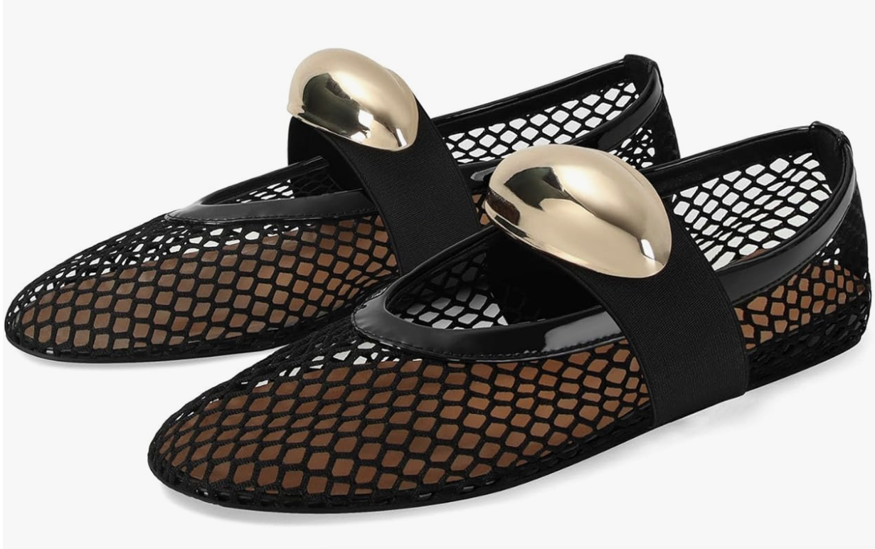 A pair of black mesh or fishnet ballerina flats featuring a pointed toe and large, sculptural gold metallic buckle details on a transparent background.
