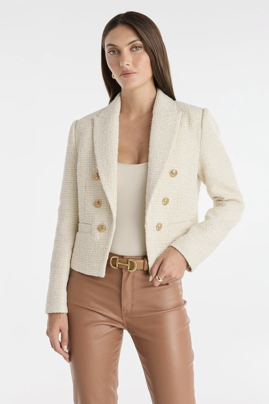 A woman wearing the Gabrielle Tweed Double Breasted Blazer in cream with gold buttons, paired with a tan belt and brown leather trousers to style with flats for women.