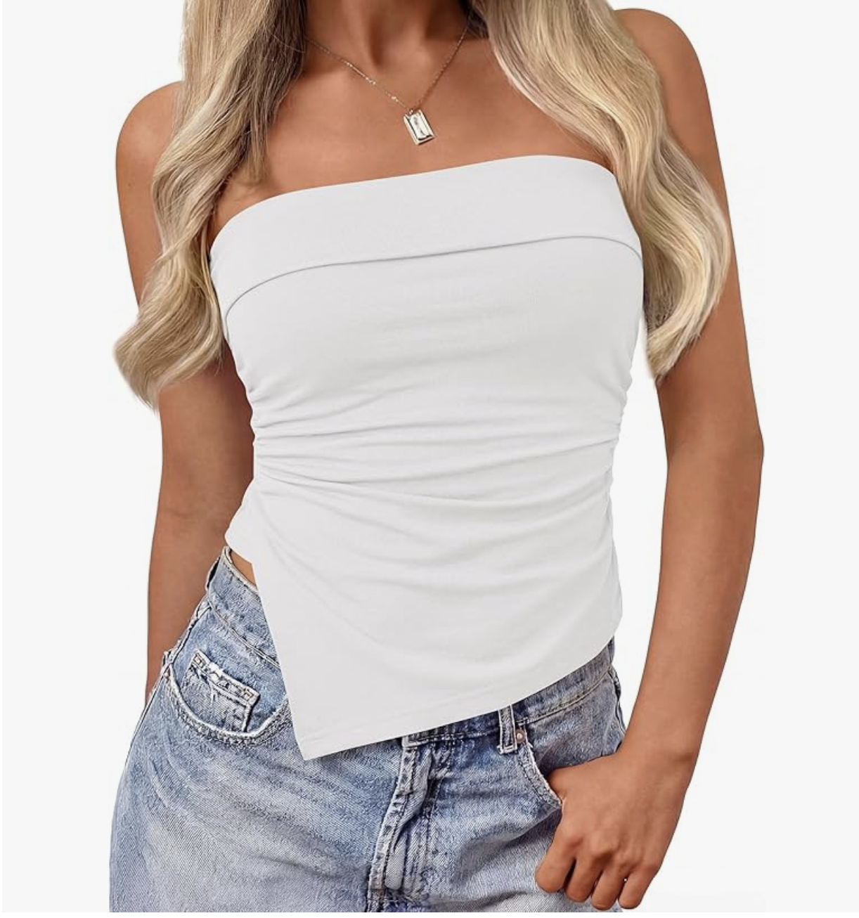 A woman wearing a white strapless asymmetrical ruched top tucked into light-wash baggy jeans to demonstrate how a fitted top balances oversized denim.