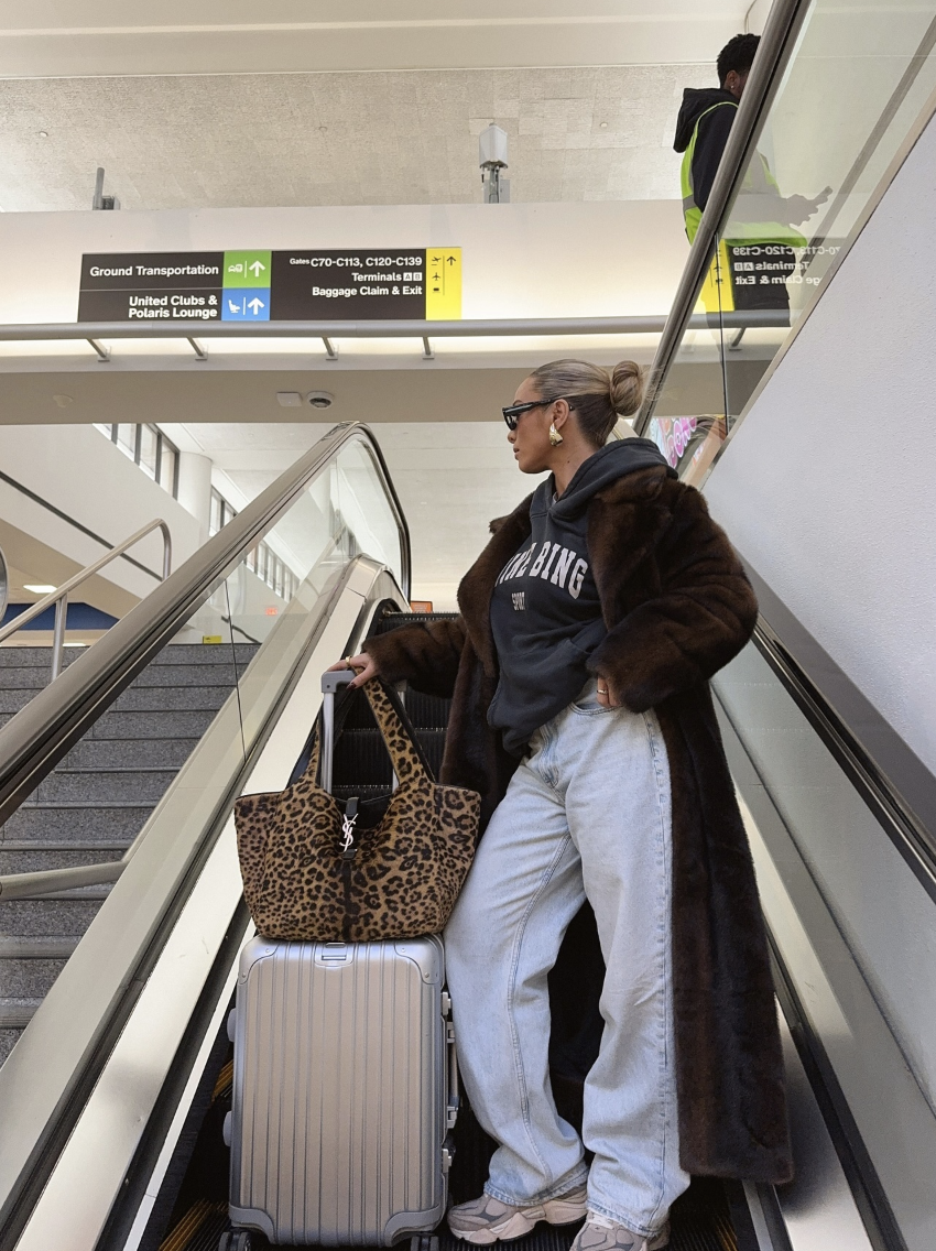 A long brown coat with a hoodie and pale jeans.