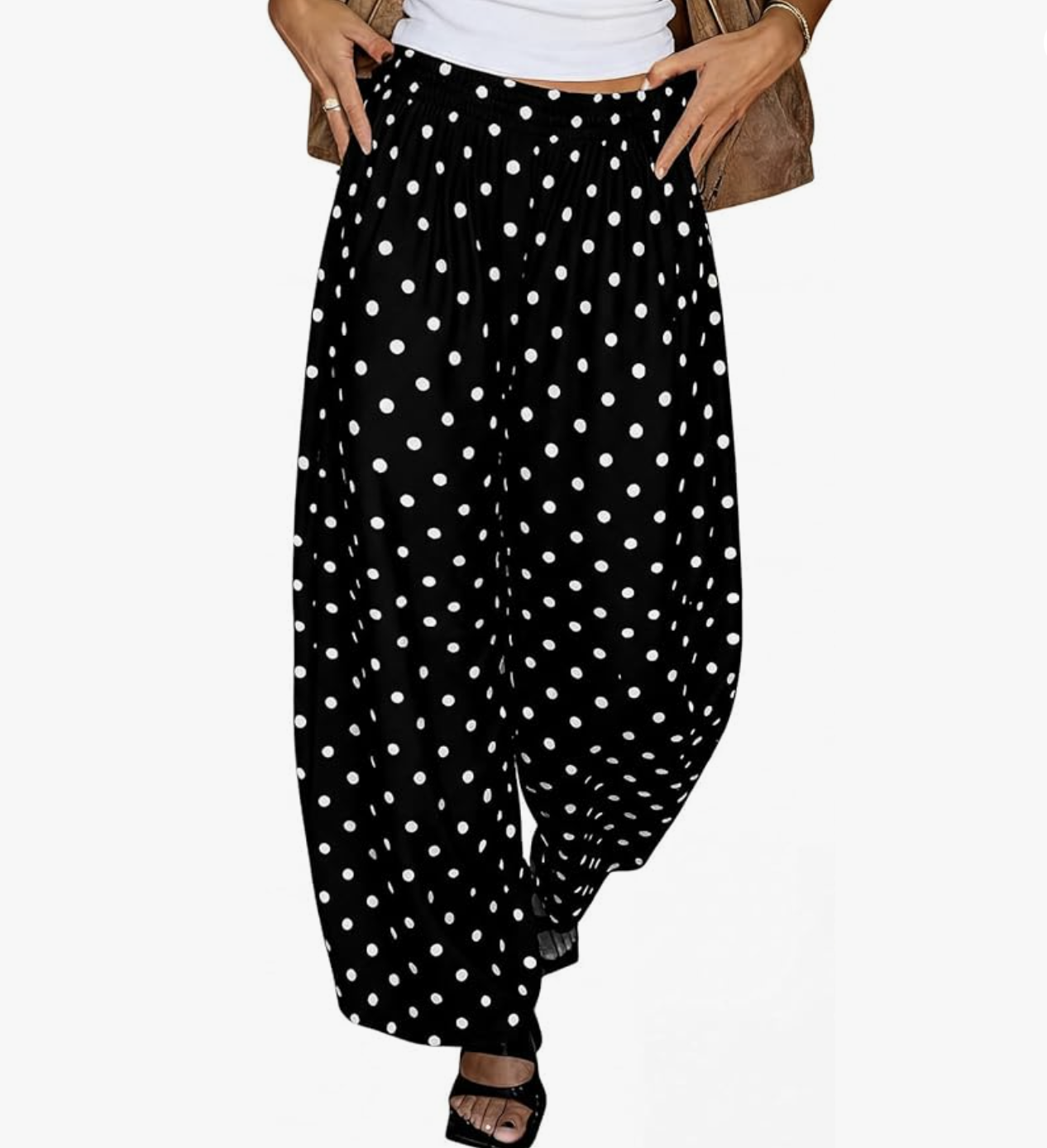 A pair of high-waisted, voluminous black pants with a white polka dot print, featuring a tapered "barrel" leg silhouette and an elastic waistband, shown from the waist down.