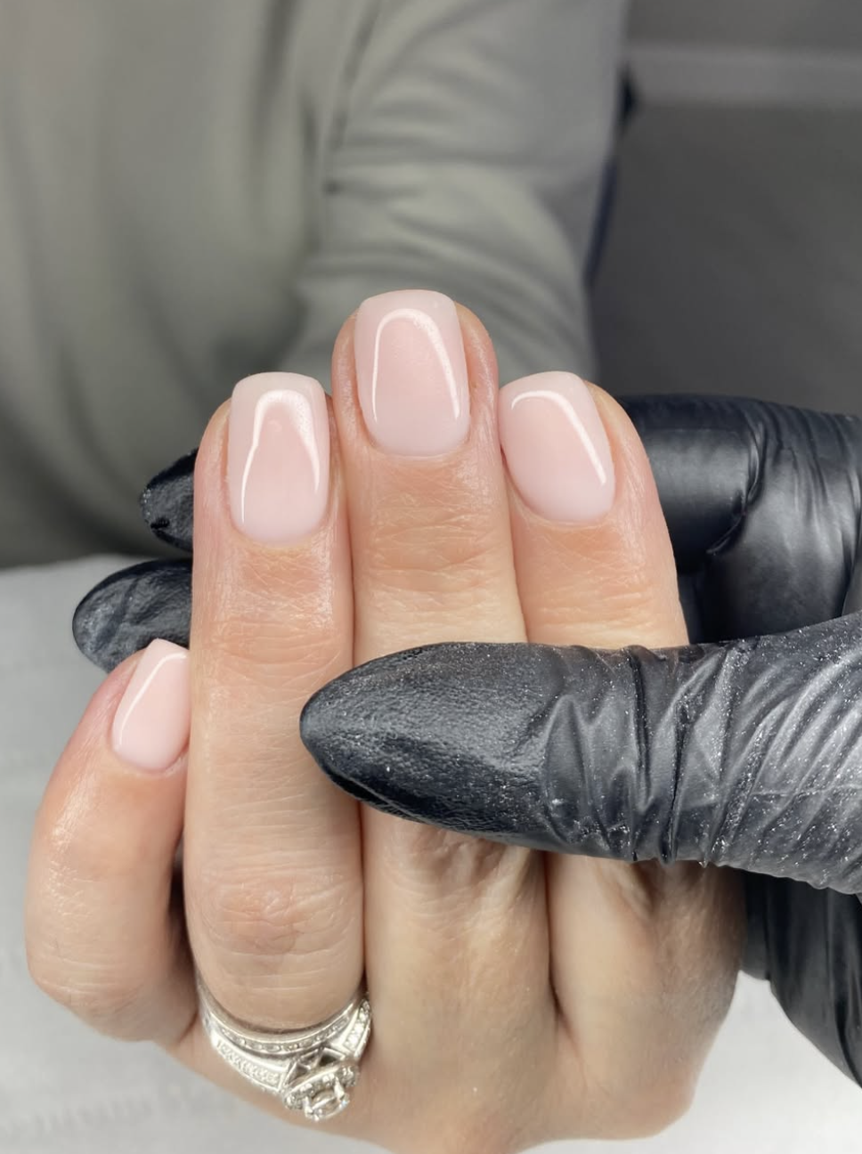 Short square nails with a sheer milky white polish and a high-gloss finish.