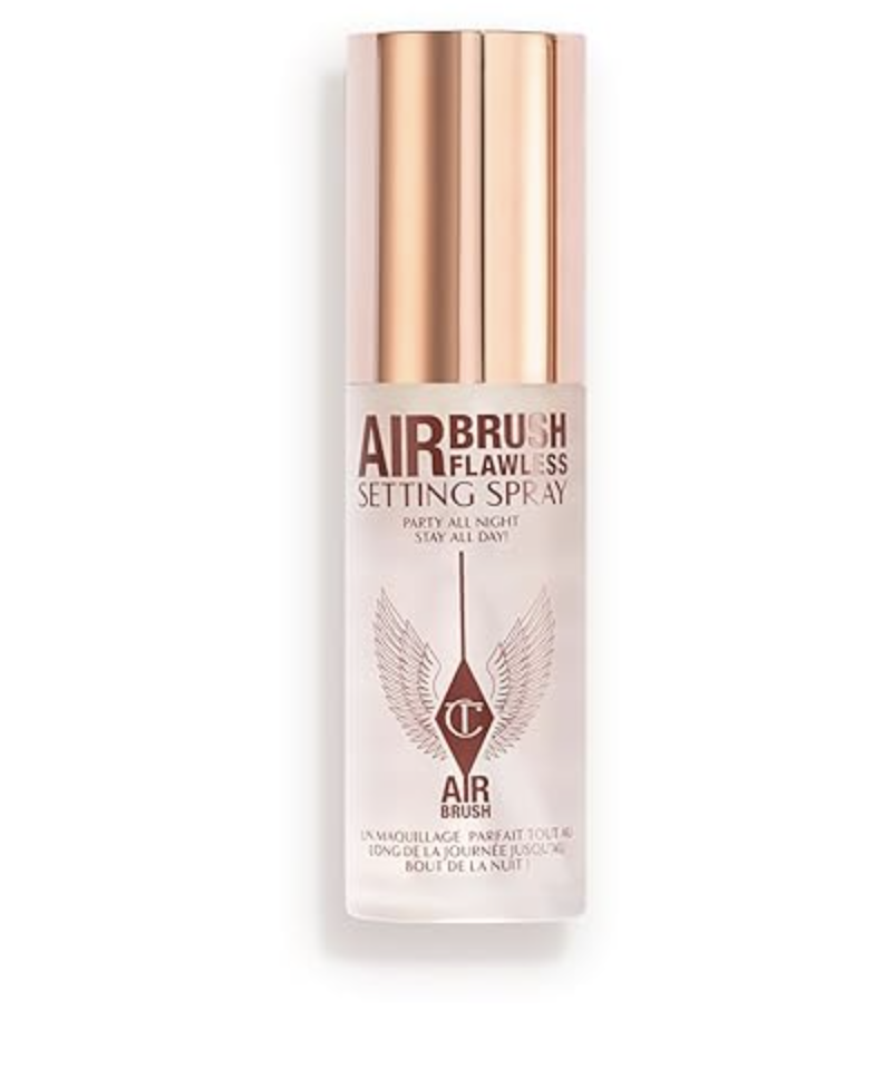 A close-up view of a bottle of Charlotte Tilbury Airbrush Flawless Setting Spray against a clean background, highlighting its elegant white and gold packaging.