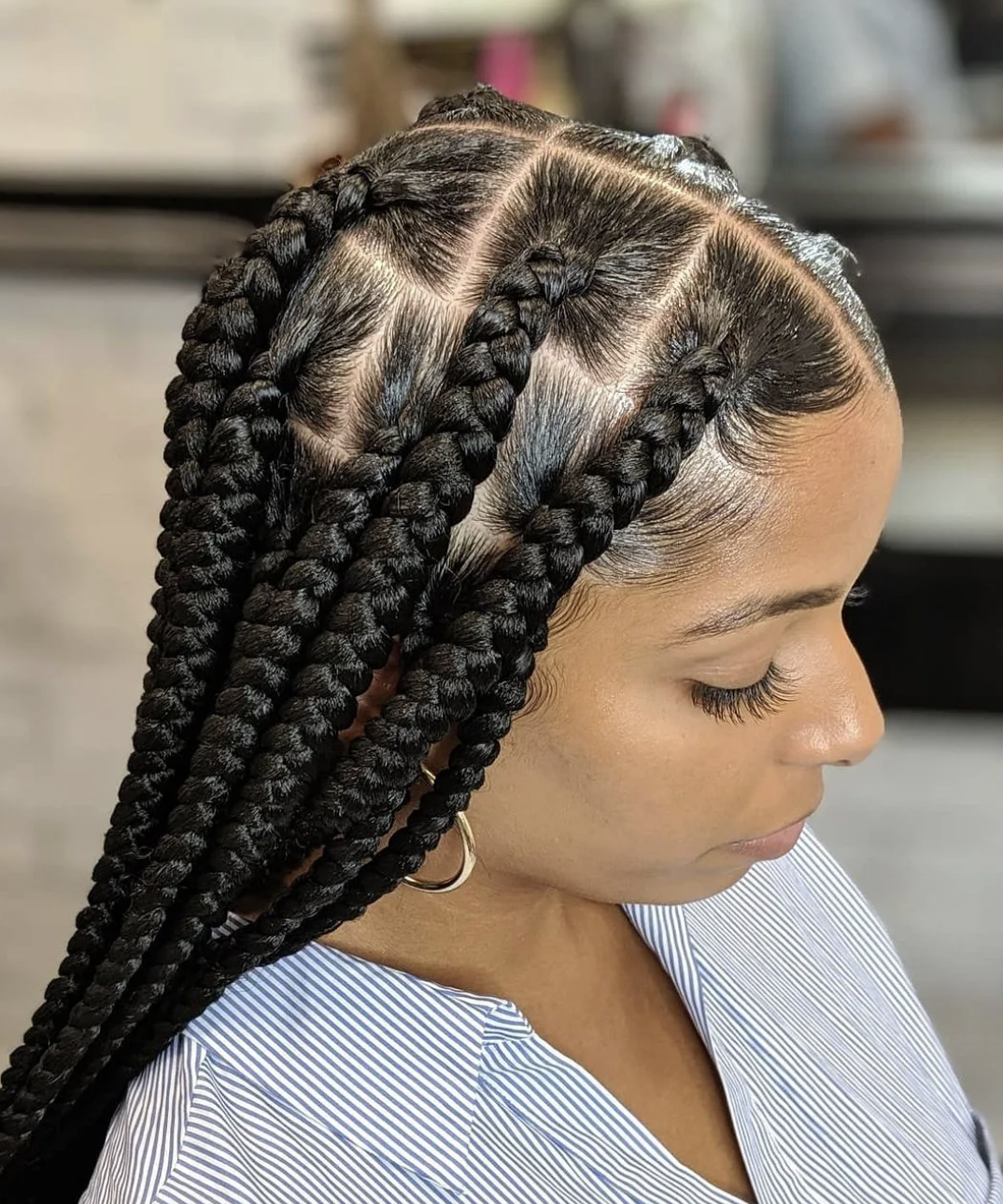 A close-up of jumbo knotless braids with large, clean square partings, showcasing a thick braided texture and a polished scalp.