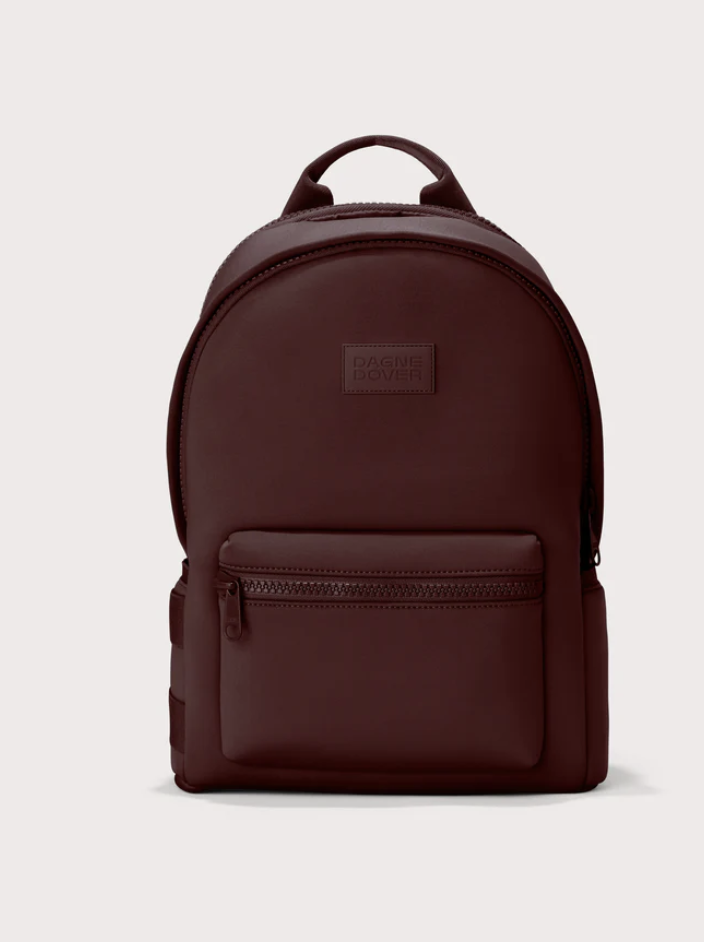 Front view of a structured oxblood burgundy neoprene backpack featuring a zippered front pocket and a tonal Dagne Dover logo patch.