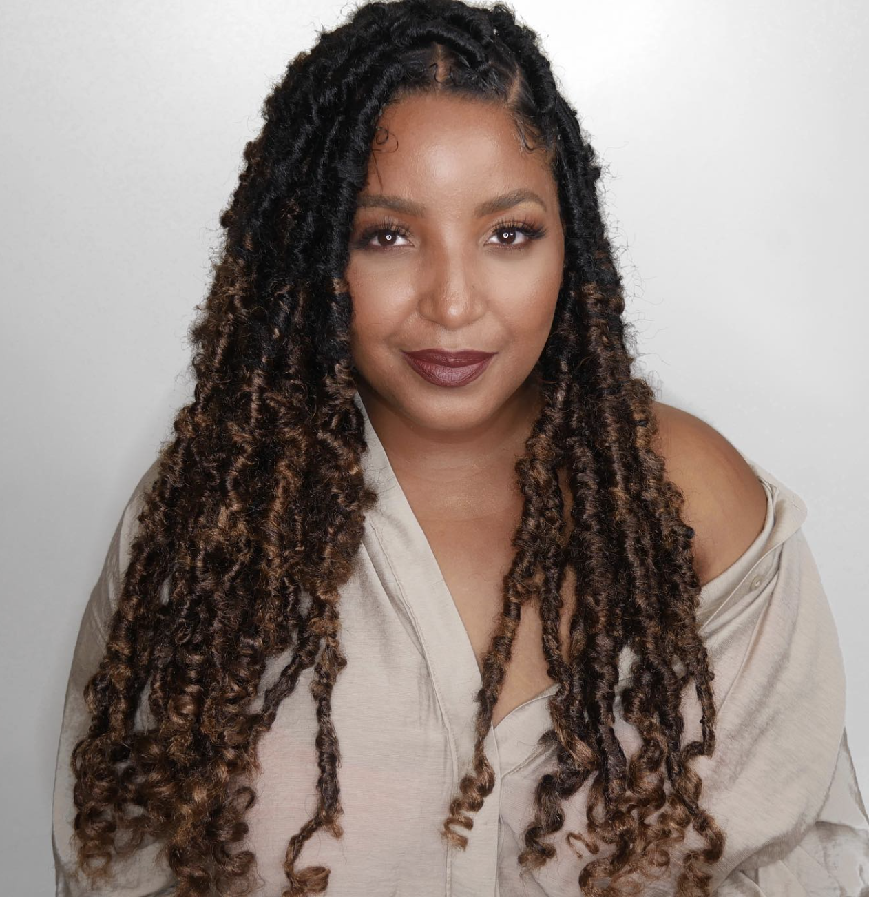 A woman with a square face shape wearing long, textured locs swept to one side, demonstrating how asymmetry creates softness and breaks up a strong jawline