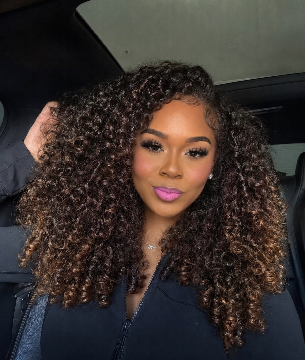 A close-up of a voluminous curly sew-in hairstyle with defined, bouncy tendrils cascading down the side.