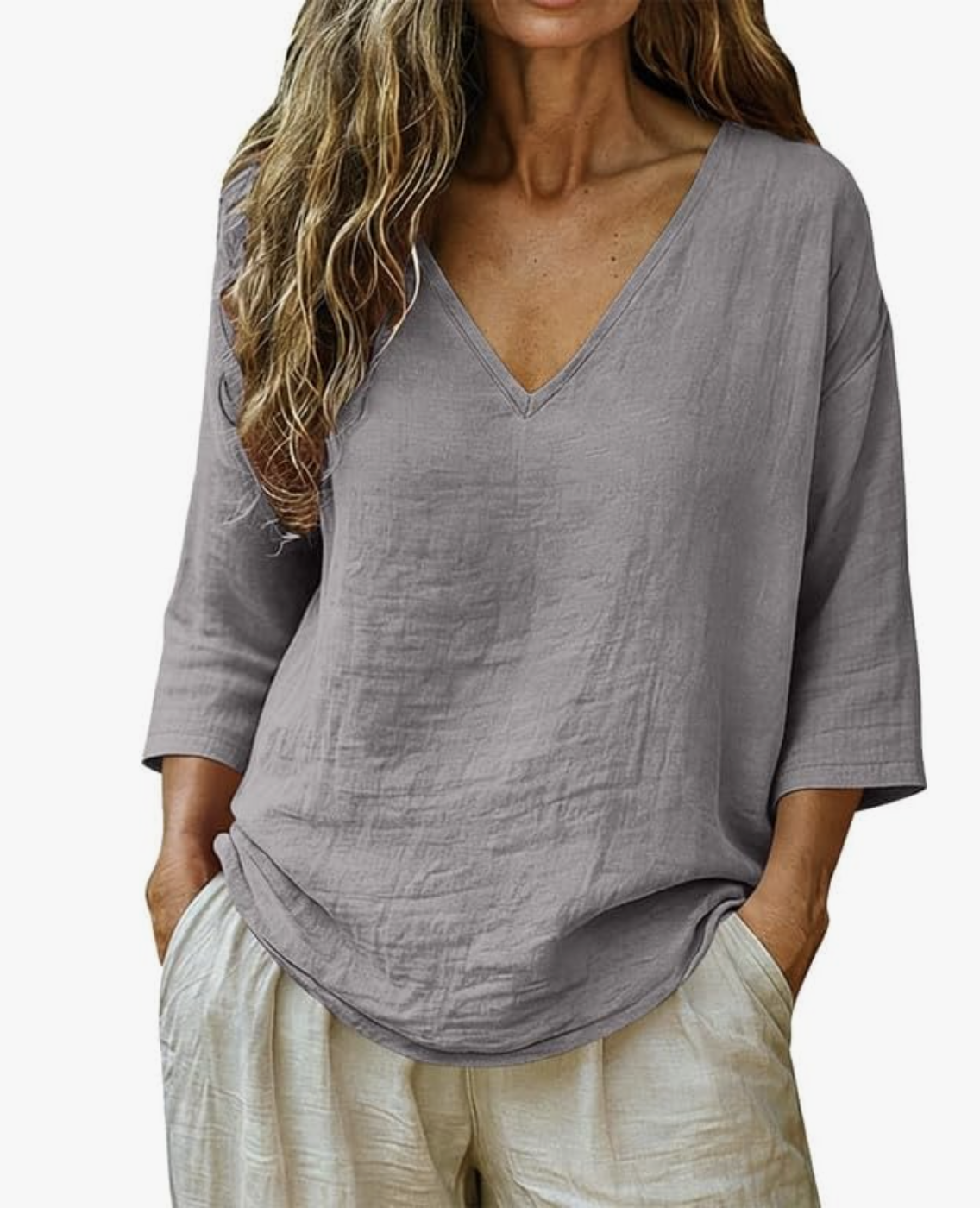 Close-up of a woman wearing a grey textured cotton-linen blouse with three-quarter roll-up sleeves, with her hand in the pocket of beige linen-blend trousers.