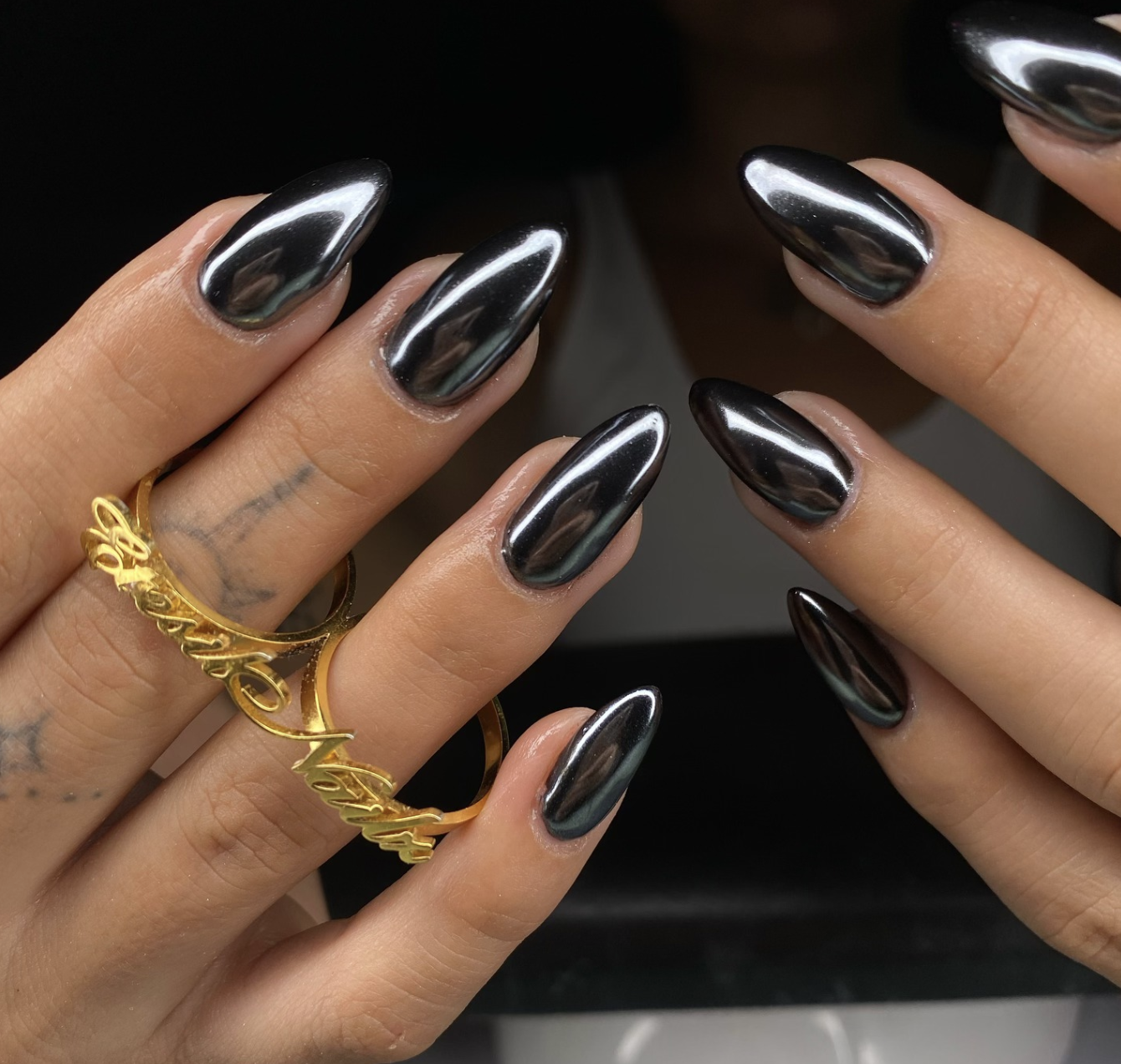Editorial close-up showcasing a viral summer manicure trend with a liquid-metal silver chrome finish on long statement nails, paired with bold gold jewelry.