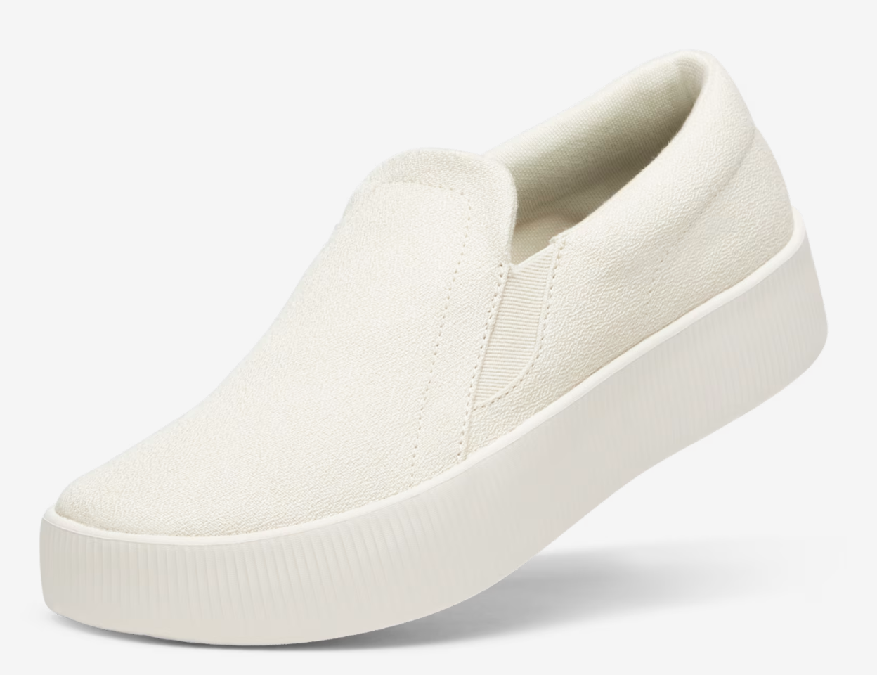 Side profile of the Vionic Women's Lounger Lift in cream white, featuring a platform sole and a minimalist slip-on design with a small circular logo detail.
