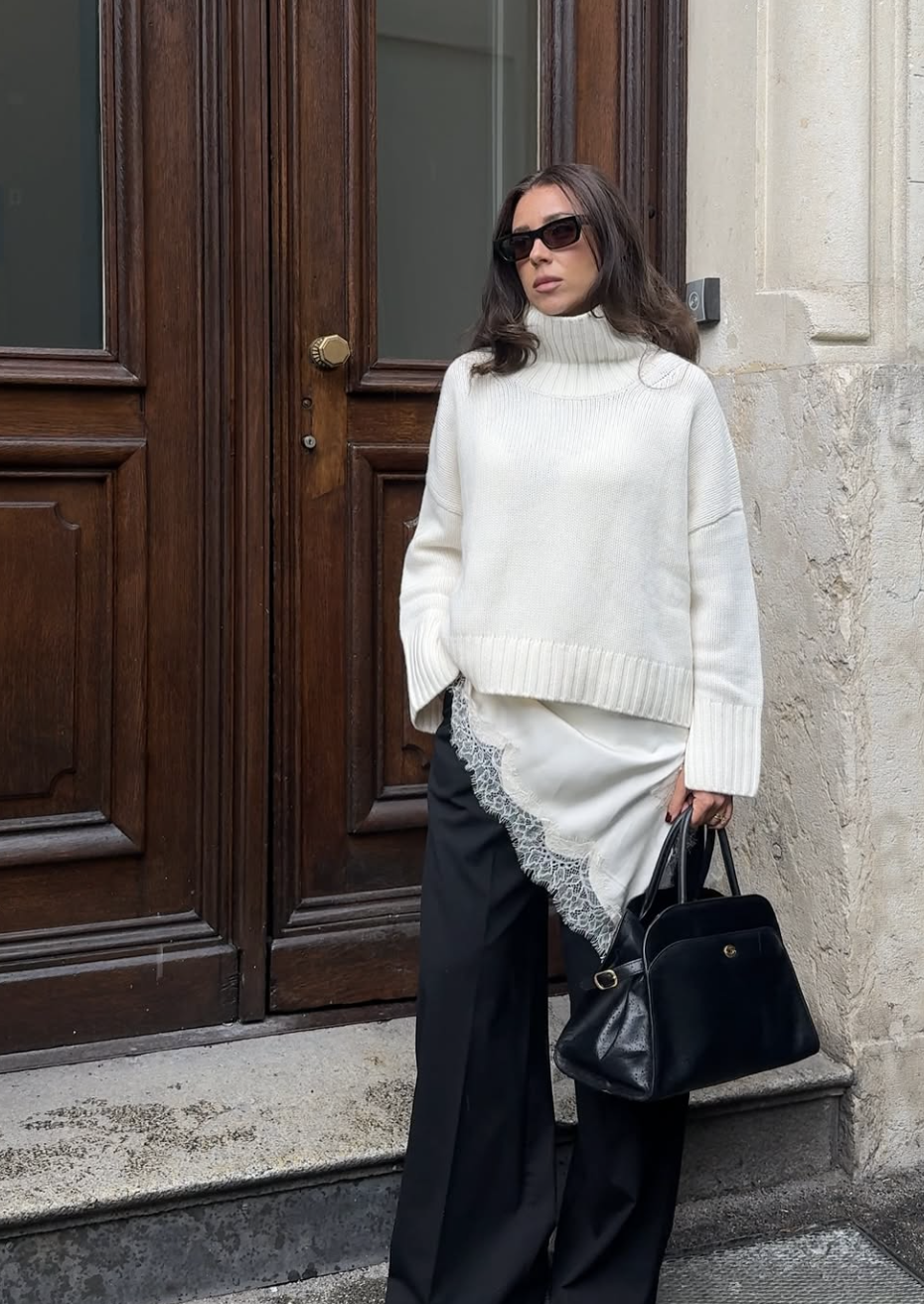 A pro stylist-inspired layering look featuring a white lace button-down shirt worn open over a black tank top and wide-leg trousers.