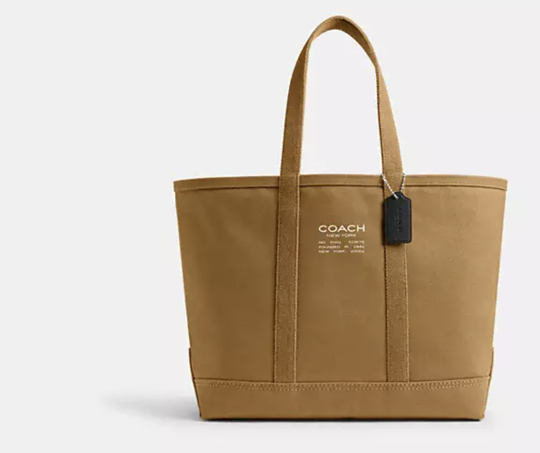 Large natural tan leather Coach Utility Tote 40 featuring structured top handles, a front logo patch, and a spacious rectangular silhouette.