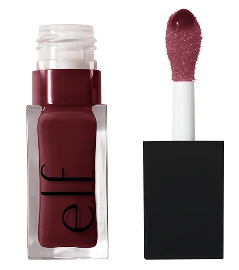 A close-up view of a bottle of e.l.f. Tinted Lip Oil shown open next to its applicator wand, coated in a glossy, rich berry-toned pink shade.