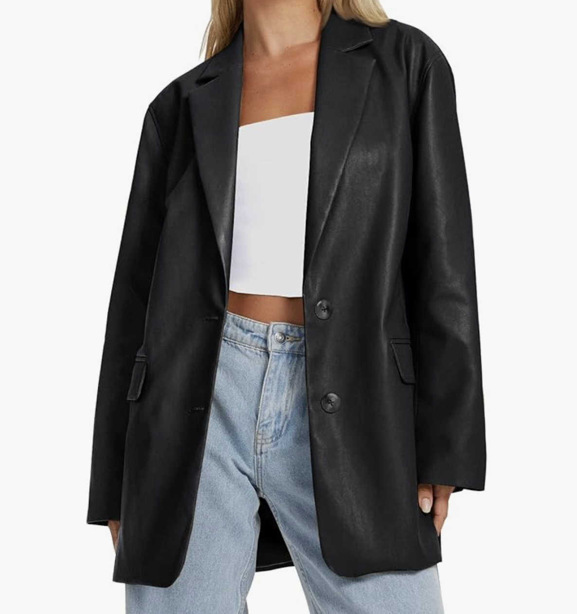 A studio product shot of a woman wearing a black faux leather blazer over a white top and light-wash blue jeans with a brown belt.