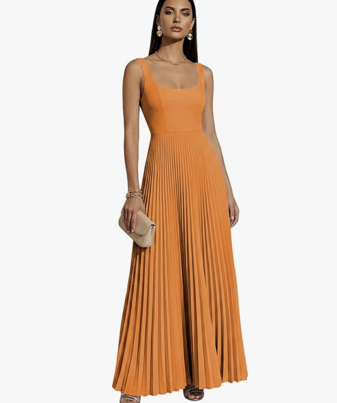 A woman wearing a vibrant burnt orange maxi dress featuring a structured tank-style bodice and a dramatic, flowy accordion-pleated skirt, styled with a straw clutch for a summer wedding look.