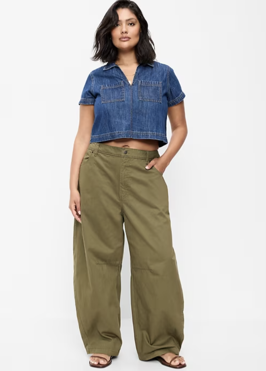 Woman wearing a faded blue short-sleeve button-down shirt tucked into high-waisted olive green barrel cargo pants with brown leather sandals.