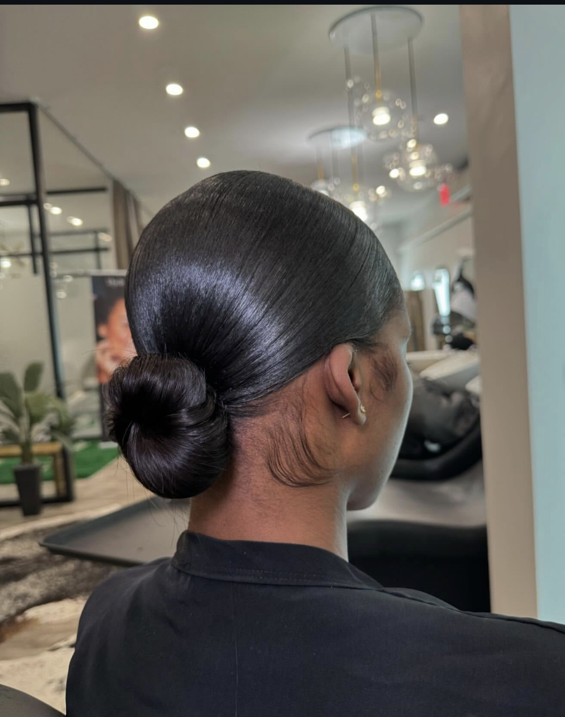 Sleek silk press hairstyle with a center part and low ponytail