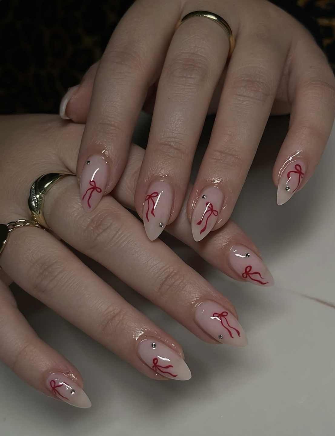 Sheer pink Christmas nails with tiny red bow nail art