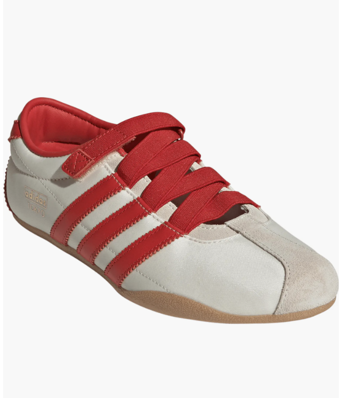 A close-up of off-white and red retro Adidas Tokyo sneakers featuring bold red stripes, wide red laces, and a classic gum sole.
