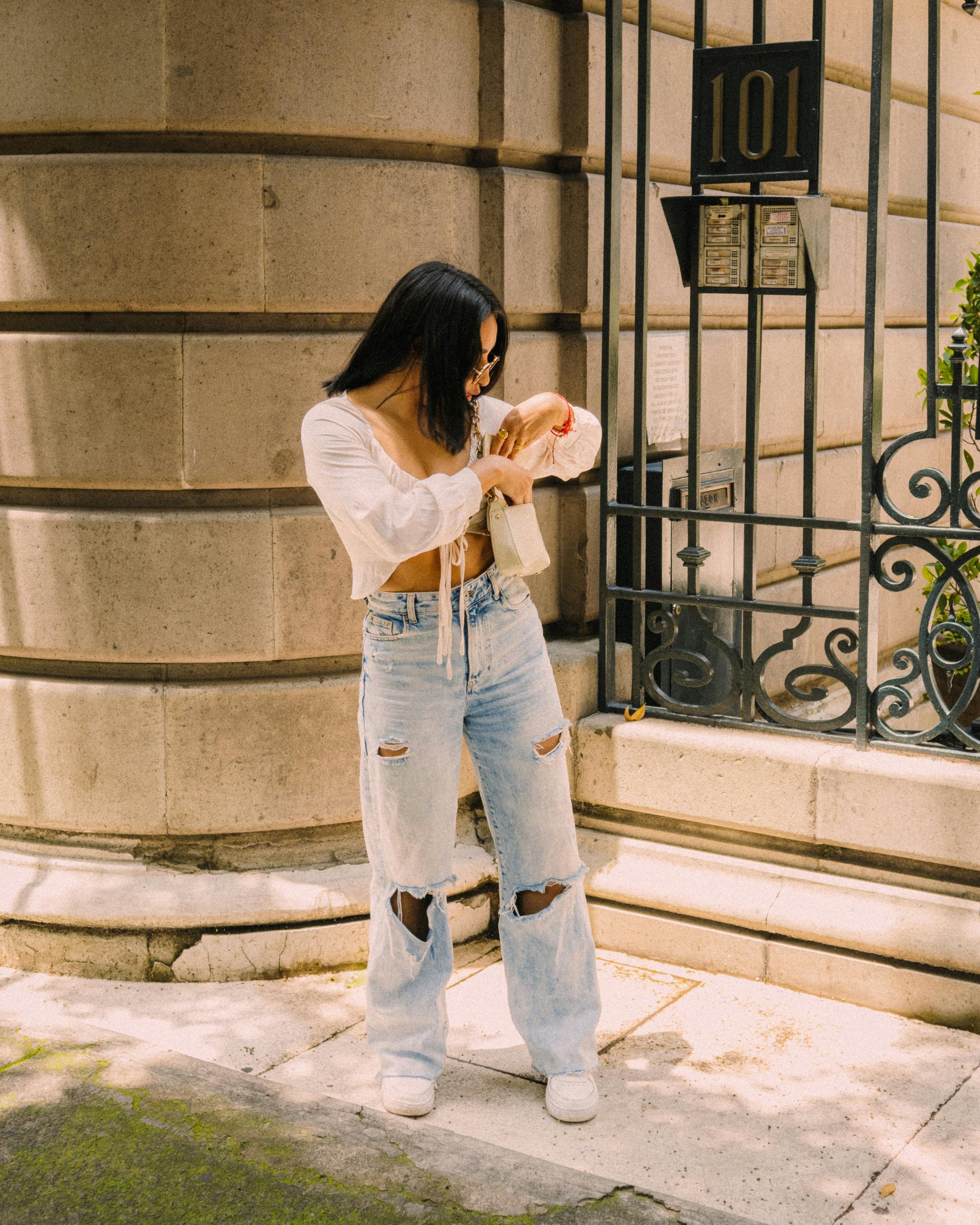 Woman Checking Purse Standing in front of Iron Fence