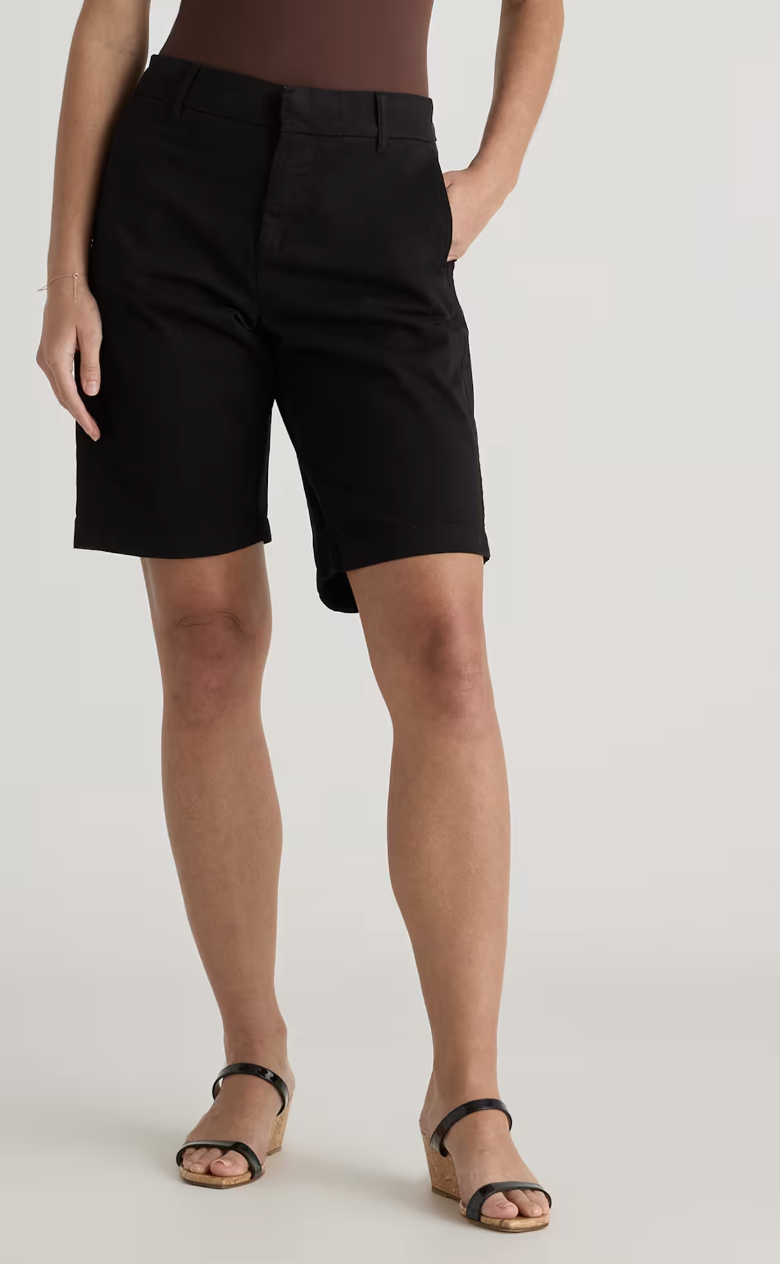 A close-up of a woman wearing black Quince organic stretch cotton chino Bermuda shorts with a defined waist and front slant pockets.