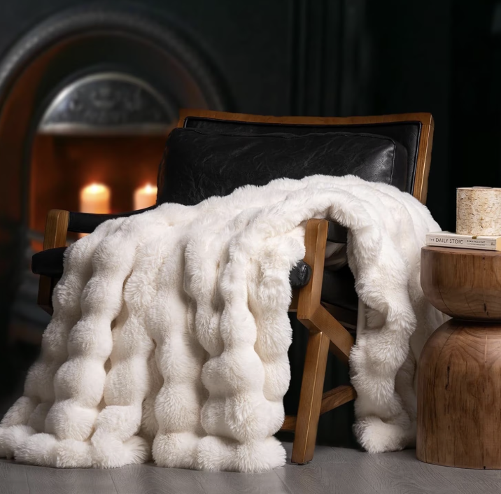 EverGrace ivory white ridgeline faux rabbit fur throw blanket with a plush bubble texture draped over a wooden armchair.