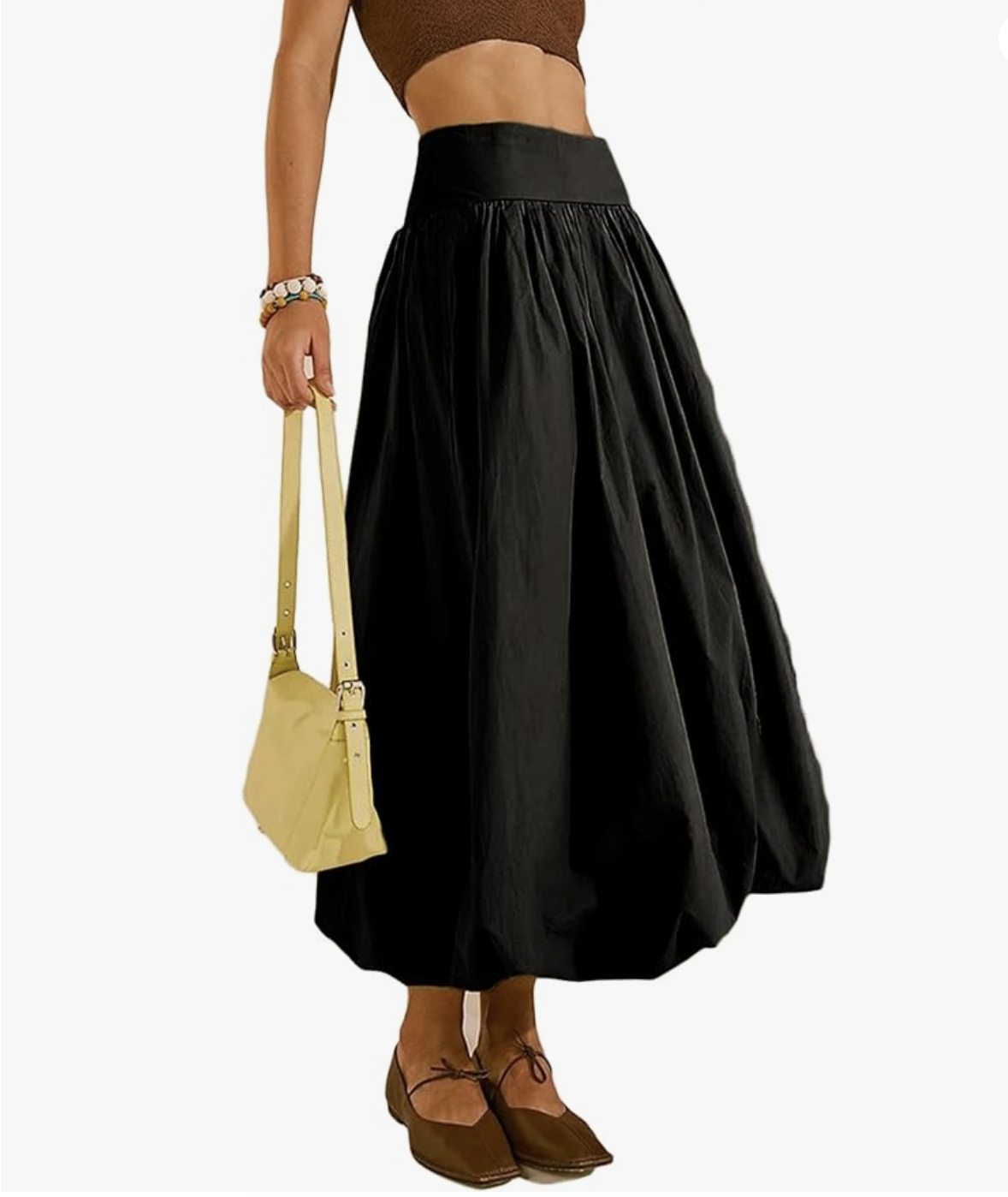 A product view of a woman wearing a voluminous black maxi skirt paired with brown mesh Mary Jane flat shoes featuring a delicate front bow tie closure.