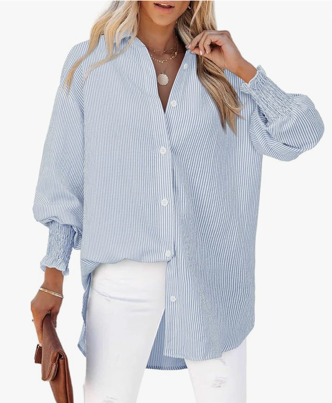 A close-up of a person wearing a light blue and white vertical striped long-sleeve button-down shirt paired with white jeans and holding a brown leather clutch bag.
