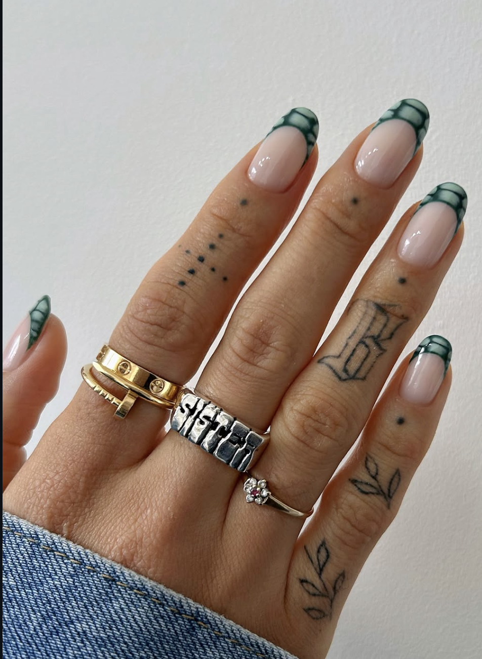 Long almond-shaped nails with a sheer nude base and sage green French tips featuring a textured crocodile skin print.