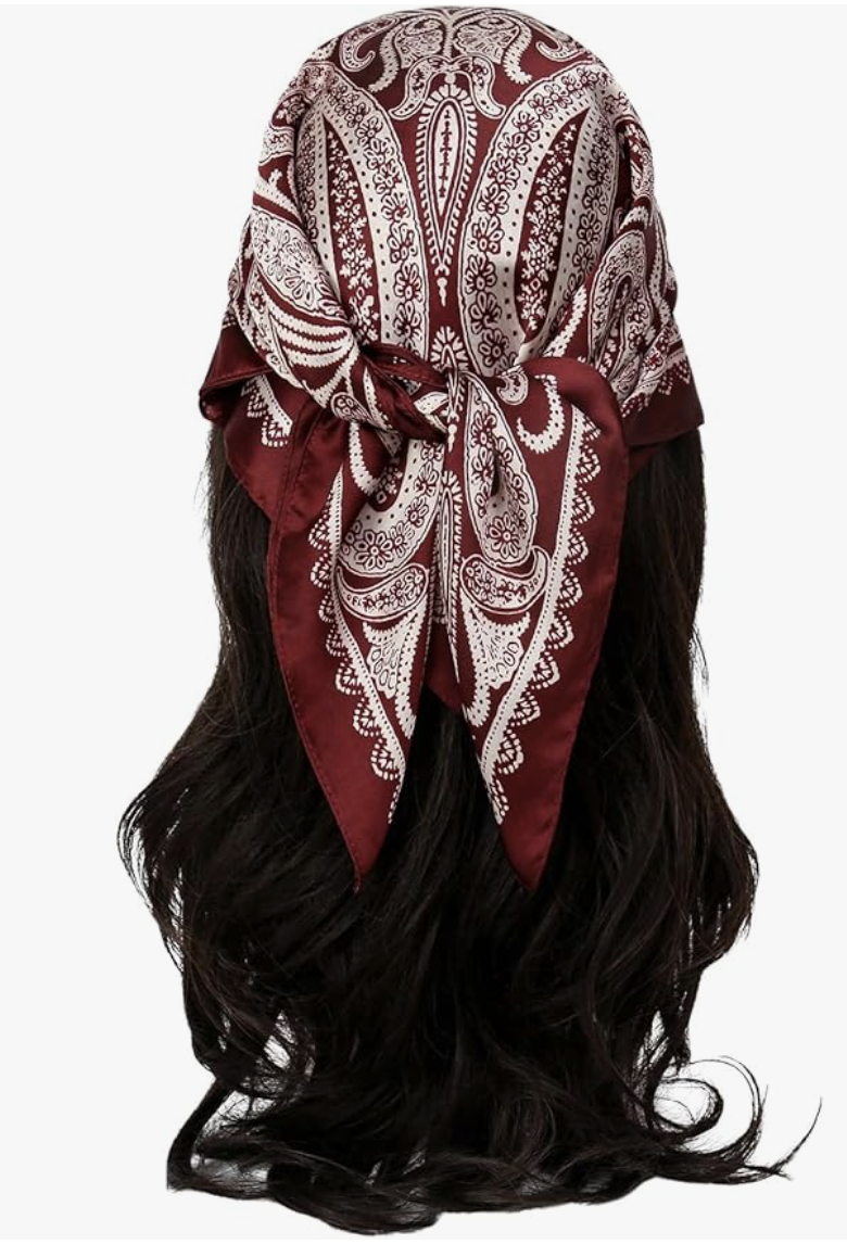 A back view of a woman with long dark hair wearing a burgundy paisley silk bandana tied as a headscarf with a knot at the back.