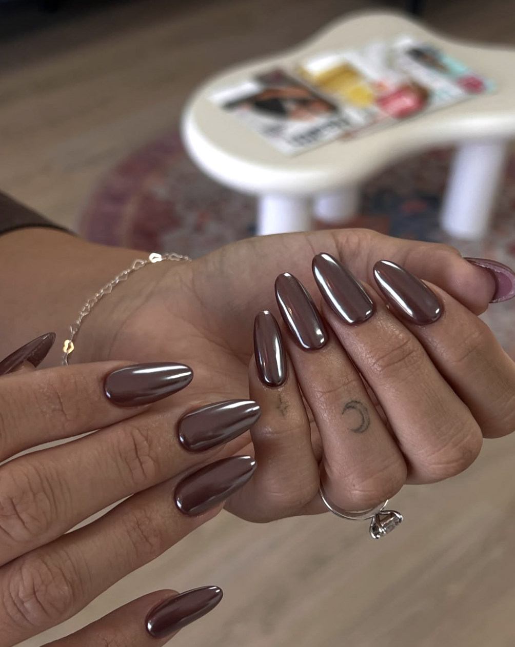 Long almond-shaped gel nails with a high-shine mocha chrome finish.
