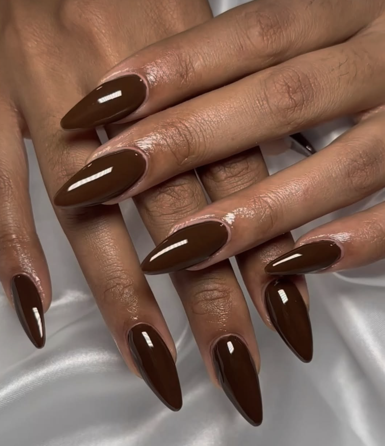 Glossy chocolate brown manicure on short nails against deep brown skin