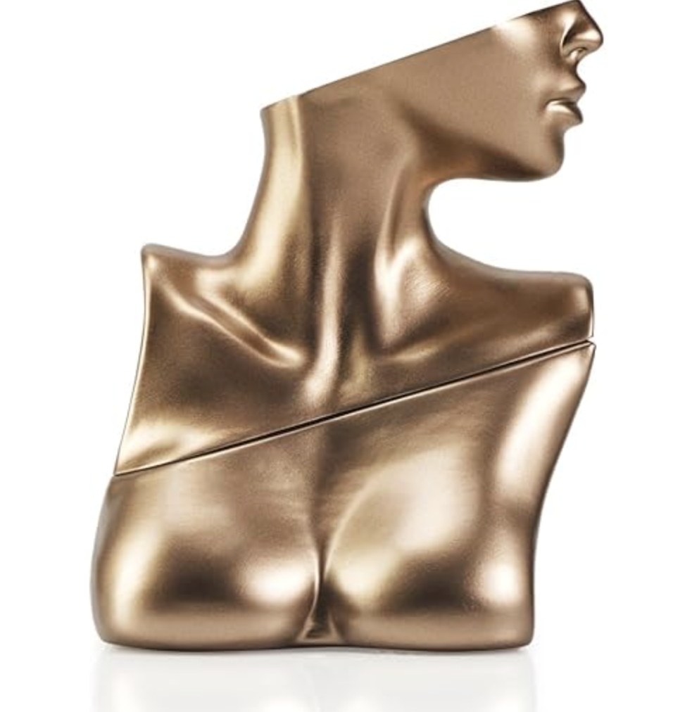 A metallic gold perfume bottle shaped like a female bust and neck, the signature packaging for the Billie Eilish Eau de Parfum.