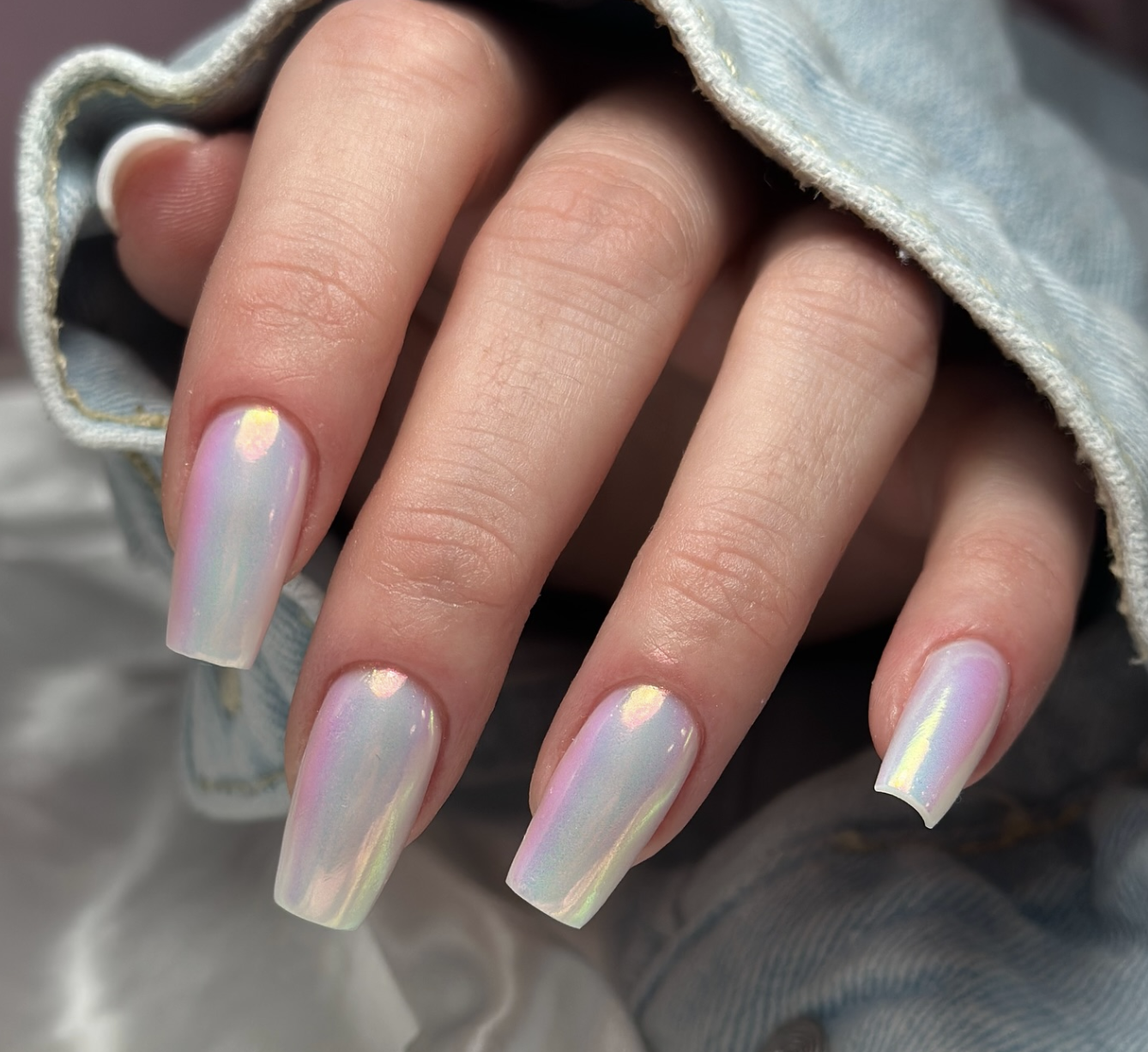 Long almond-shaped gel nails with a full-coverage holographic silver glitter finish that reflects rainbow colors.