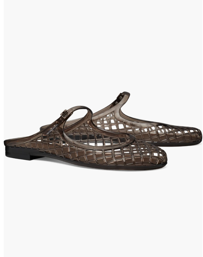 A close-up product view of a pair of translucent, smoky brown woven lattice jelly mule flats featuring an open back and a subtle brand logo on the side strap.