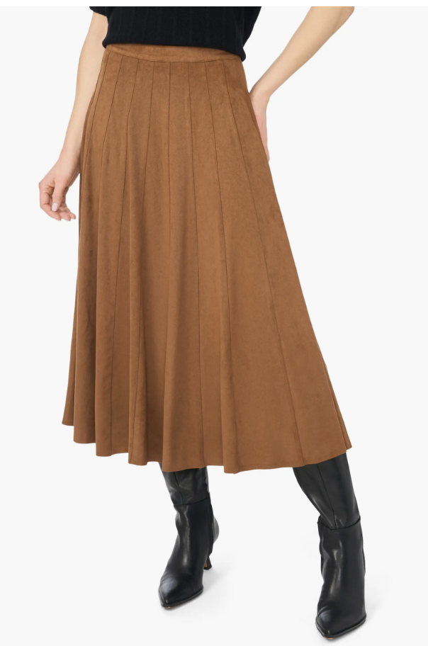 A close-up shot of a model wearing the Halogen Paneled Pintuck Faux-Suede Midi Skirt in a warm cognac brown, paired with tall black leather boots.